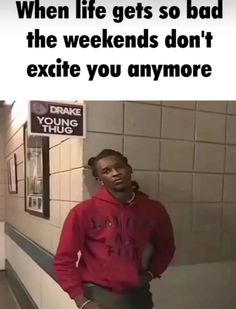 a man in a red hoodie standing next to a wall with a sign that says, when life gets so bad the weekends don't exite you anymore