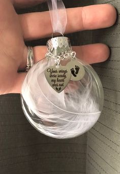 a hand holding a clear glass ornament with a heart on it's side