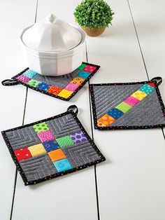 three patchwork coasters sitting on top of a white table next to a potted plant