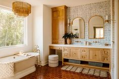 a bathroom with a tub, sink and large mirror in it's center area