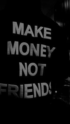 black and white photograph of a man holding a sign that says make money not friends