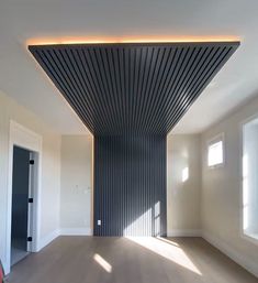 an empty room with wood flooring and black slats on the ceiling above it