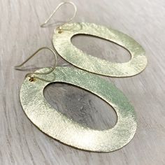 "These handcrafted earrings are modern and chic! Large gold circular hoops measuring over 2 inches long by 1.5 inches wide dangle from matching fish hooks. Earring material is brass dipped in brushed gold and lacquered with a protective varnish to prevent tarnish. Such beautiful texture! The earrings measure approximately 2.75\" in total length. A fabulous chunky look in a super lightweight style! Item is carefully packaged and shipped via USPS in a sturdy protective mailer. Check out more fabul Chic Oval Earrings For Everyday, Chic Oval Earrings For Gift, Chic Oval Metal Jewelry, Modern Gold Hoop Linear Earrings, Chic Hammered Metal Earrings, Gold Circle Single Earring, Chic Gold Hammered Earrings, Gold Single Circle Earring, Modern Oval Metal Earrings