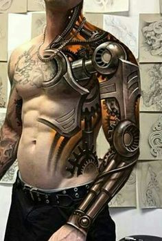 a man standing in front of a wall with tattoos on his chest and arms, holding a mechanical arm