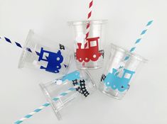 four cups with different designs and colored straws on the top one has a train design