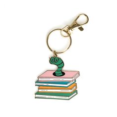 a keychain that has a book and a snake on it, sitting on top of some books