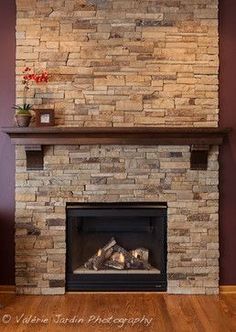 a living room with a fire place in the center and wood flooring on the other side