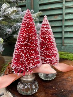 two small red christmas trees sitting on top of a wooden table