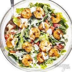 a salad with shrimp and lettuce in a glass bowl on a white background