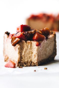 a piece of cheesecake with strawberries and nuts is on a white tablecloth