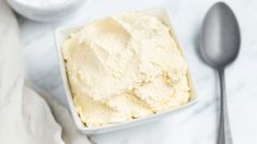 a white bowl filled with ice cream next to two spoons