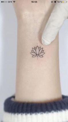 a woman's wrist with a small lotus tattoo on the left side of her arm