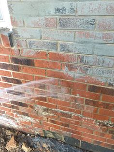 a fire hydrant spewing water on the side of a brick building