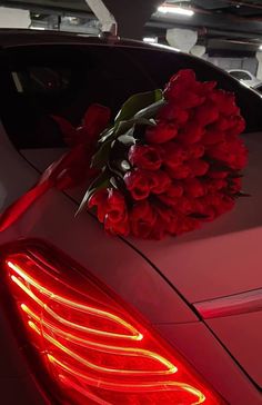 a bouquet of red roses is sitting on the hood of a car in a parking garage