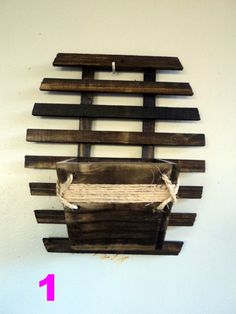 a wooden wall hanging on the side of a white wall with rope and wood slats attached to it