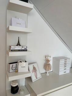 a white desk topped with shelves filled with books and other items next to a stair case