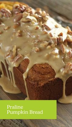 a loaf of bread covered in icing and nuts on top of a wooden table