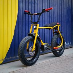 a yellow and black bike parked next to a blue wall