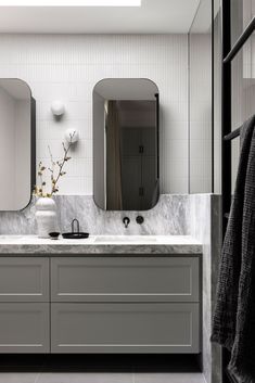 a bathroom with marble counter tops and two mirrors on the wall, along with white cabinets