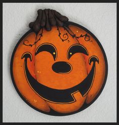 an orange and black pumpkin with a face painted on it's side, hanging from the wall