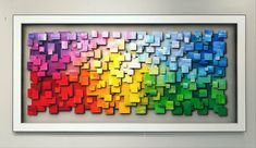 an art piece is displayed in front of a white frame with multicolored squares on it