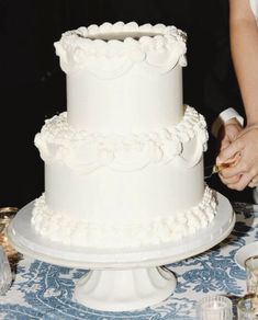 a man and woman cutting into a white wedding cake