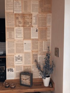 a wooden table topped with a potted plant next to a wall covered in newspaper