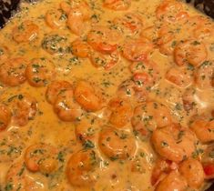 a skillet filled with shrimp and cheese covered in sauce