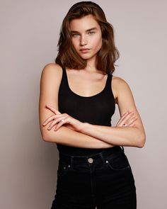 a woman in black shirt and jeans posing for a photo with her arms folded over her chest