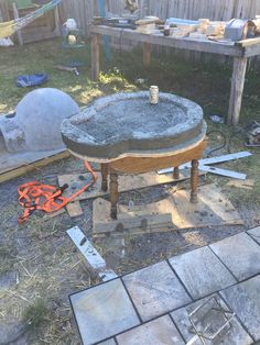 an old wooden table sitting in the middle of a yard next to a pile of junk