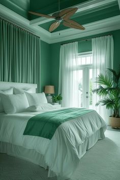 a bedroom with green walls, white bedding and a ceiling fan in the corner