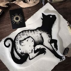 a black and white drawing of a cat on top of a paper with some ink