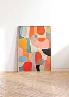 an abstract painting on the wall next to a chair in a room with hard wood flooring