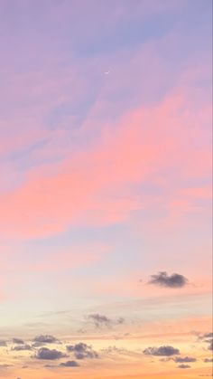 an airplane is flying in the sky with pink and blue clouds behind it at sunset