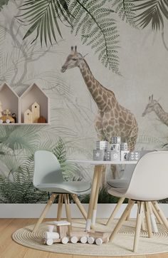 two giraffes are standing in front of a wall mural with palm leaves