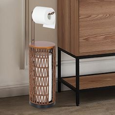 a toilet paper dispenser sitting next to a wooden cabinet with a roll of toilet paper in it