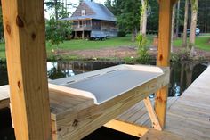 a wooden dock with a metal tray on it's end and a house in the background