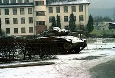 two tanks are parked in front of a building on a snowy day with snow covering the ground