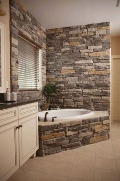 a bathroom with a stone wall and tub next to a window in the shower area