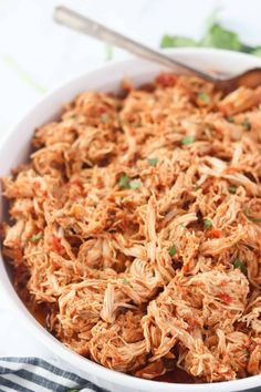 a white bowl filled with shredded chicken and garnished with cilantro