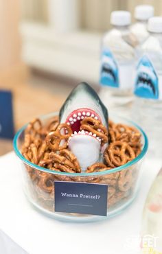 a glass bowl filled with pretzels and a shark fin sticking out of it's mouth