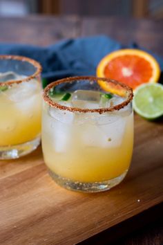 two margaritas on a cutting board with orange slices