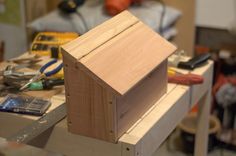 a wooden birdhouse sitting on top of a table next to a piece of wood