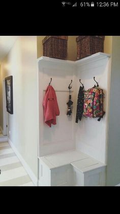 an entryway with two coats hanging on hooks and one coat rack in the corner