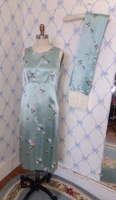 "This gorgeous silk dress dates to the 1990's and is wonderful condition, with the exception of a few light stains.  It is fashioned out of silk brocade and is fully lined. The fabric is a beautiful aqua silk embroidered with pink, gold, and white flowers, accented with dark green leaves.  The dress is sleeveless, and the armholes are cut in at the shoulder. The front neckline has a high scoop neck and an empire waistline. The back neckline plunges to a deep V. The skirt has an A-line silhouette and is below-knee length--depending on your height. Bust: 36 Waist: 32 Under arm to hem: 36 Shoulder to empire waist: 13 1/2 Shoulder to back waist: 14 Scarf: 52\" w 6\" fringe A beautiful, comfortable dress to wear to your next party!" Spring Bohemian Fitted Silk Dress, Spring Evening Silk Dress With Bias Cut, Spring Bias Cut Silk Evening Dress, Vintage Satin Summer Dresses, Vintage Silk Bias Cut Dress, 1990s Dress, Vintage Veils, Empire Waistline, Scoop Neck Dress