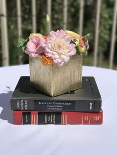 two books stacked on top of each other with flowers in the middle sitting on a table