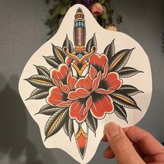 a person holding up a sticker with an image of a flower and arrow on it