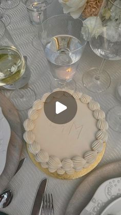 a table topped with a white cake covered in frosting and surrounded by silverware