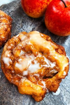 apple cinnamon rolls with icing and two apples on the side, one is half eaten