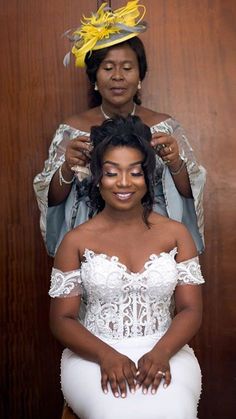 a woman is getting her hair done by another woman in front of a wooden wall